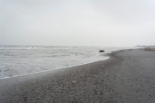 Overcast day, beach with a gray sky and many seashells brought by the storm, the sea is rough, lido Adriano, Ravenna.