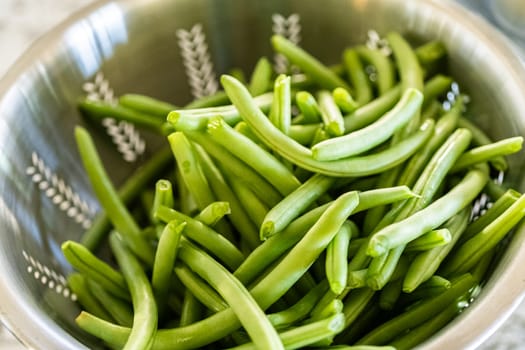 Watch as fresh green beans are beautifully roasted to perfection on a baking sheet with a silicone mat, adding a burst of flavor to your meal.