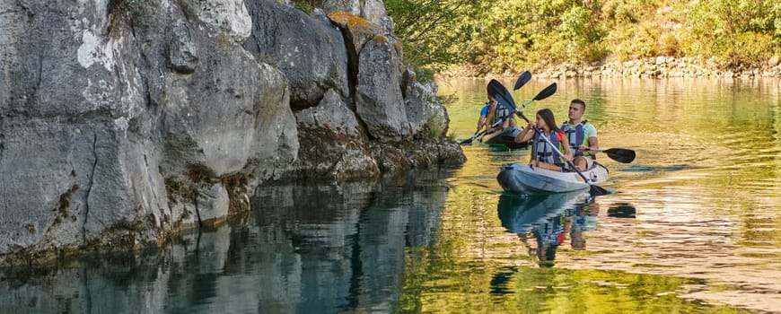 A group of friends enjoying having fun and kayaking while exploring the calm river, surrounding forest and large natural river canyons.