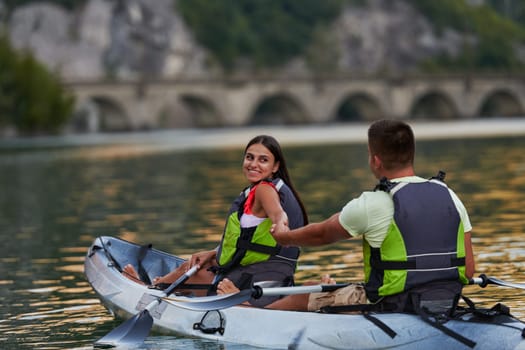 A young couple enjoying an idyllic kayak ride in the middle of a beautiful river surrounded by forest greenery.