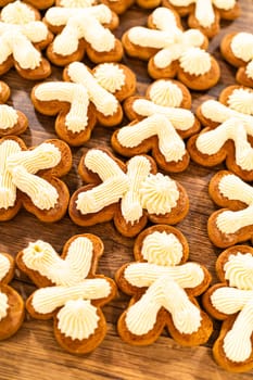 Making gingerbread man cookie sandwiches filled with eggnog buttercream, arrayed on a rustic wooden table, ideal for heartfelt Christmas gifting.