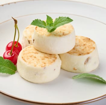 Round small fried cheesecakes on a plate. Background white