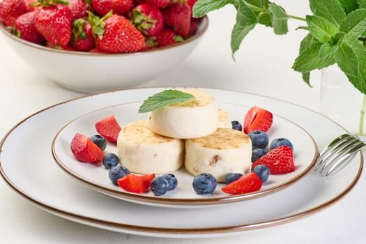 Stack of four cheesecakes on a plate with berries, blueberries, strawberries and cherries. Background white