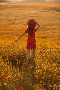 A woman in a red dress stands in a field of yellow flowers. She is wearing a red hat and has her hand up in the air. The scene is peaceful and serene, with the woman enjoying the beauty of the flowers