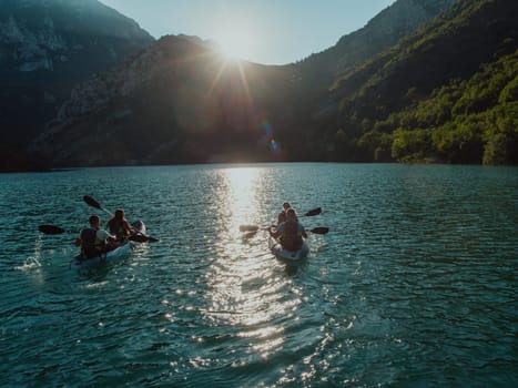 A group of friends enjoying fun and kayaking exploring the calm river, surrounding forest and large natural river canyons during an idyllic sunset