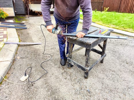 Craftsman Cutting Metal Column With Grinder Outdoors. Man using a grinder on metal column, creating sparks