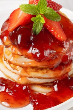 Mini pancakes with strawberry jam and strawberries.