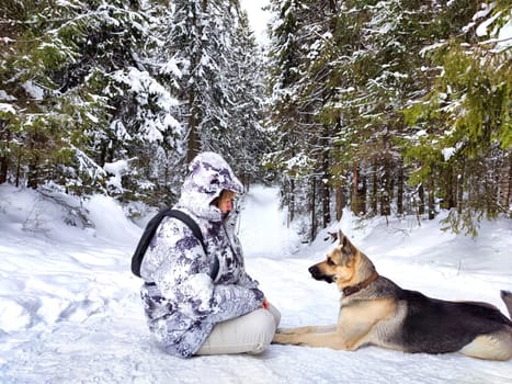 Adult girl or mature lady with shepherd dog in winter nature landscape in forest. Middle aged woman training big shepherd dog in cold day. Friendship, love, communication, fun, hugs