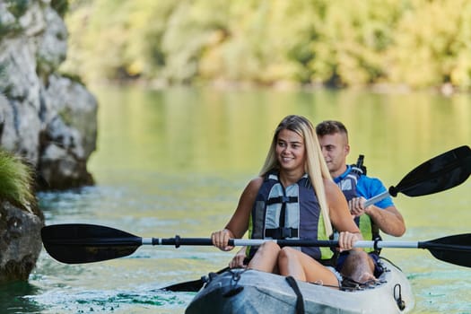 A young couple enjoying an idyllic kayak ride in the middle of a beautiful river surrounded by forest greenery.