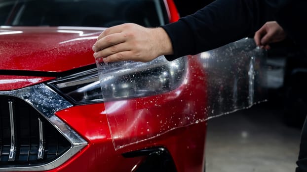 The process of applying protective vinyl film to car headlights in detailing