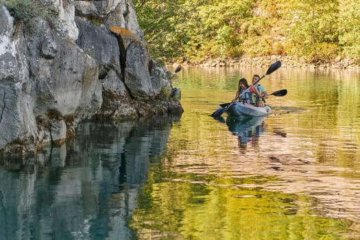 A young couple enjoying an idyllic kayak ride in the middle of a beautiful river surrounded by forest greenery.