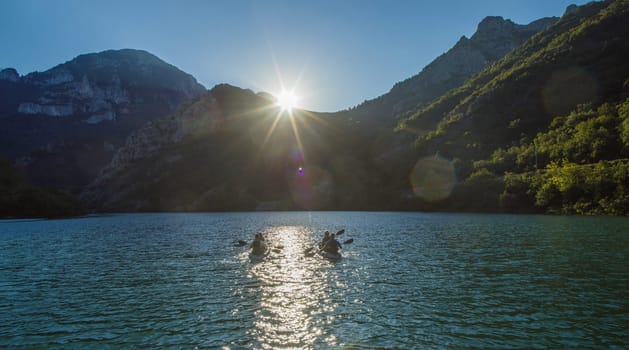 A group of friends enjoying fun and kayaking exploring the calm river, surrounding forest and large natural river canyons during an idyllic sunset