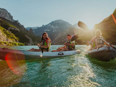 A group of friends enjoying fun and kayaking exploring the calm river, surrounding forest and large natural river canyons during an idyllic sunset