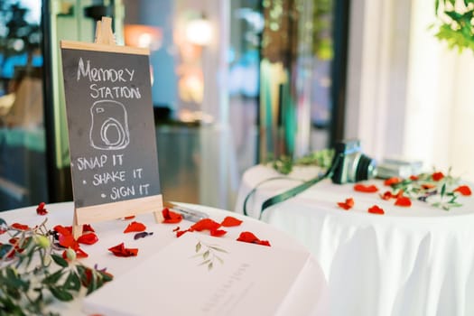Sign on the table among red petals. Caption: Memory station. High quality photo