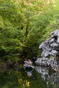 A young couple enjoying an idyllic kayak ride in the middle of a beautiful river surrounded by forest greenery.