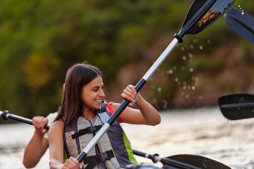 A young couple enjoying an idyllic kayak ride in the middle of a beautiful river surrounded by forest greenery.