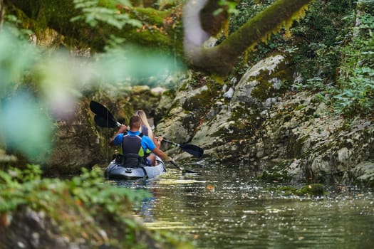 A young couple enjoying an idyllic kayak ride in the middle of a beautiful river surrounded by forest greenery.