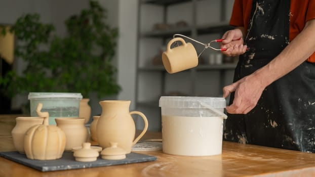 Close-up of a potter's hands glazing a ceramic mug