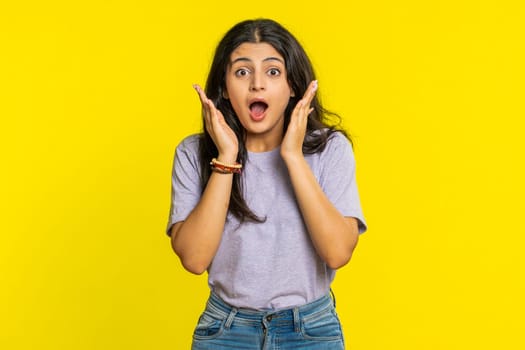 Oh my God, Wow. Excited amazed winner woman raising hands in surprise looking at camera with big eyes, shocked by sudden victory celebrating success achievement good news. Girl on yellow background