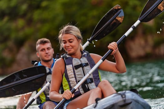 A young couple enjoying an idyllic kayak ride in the middle of a beautiful river surrounded by forest greenery.