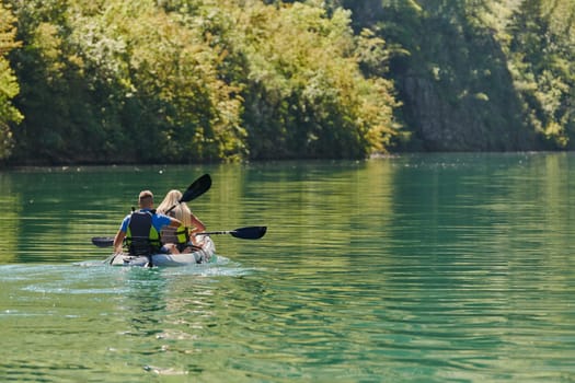 A young couple enjoying an idyllic kayak ride in the middle of a beautiful river surrounded by forest greenery.