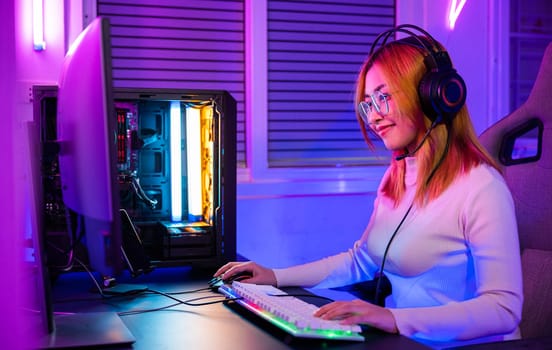 Young player woman wearing gaming headphones intend to do playing live stream games online at home, Happy Gamer endeavor plays online video games tournament with computer desktop with neon lights