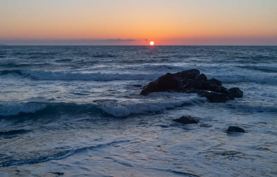 stones in the Mediterranean sea near the beach rocks against the backdrop of sunset