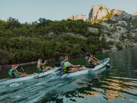 A group of friends enjoying having fun and kayaking while exploring the calm river, surrounding forest and large natural river canyons.