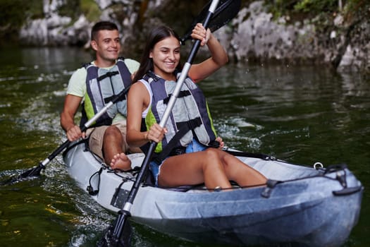 A young couple enjoying an idyllic kayak ride in the middle of a beautiful river surrounded by forest greenery.