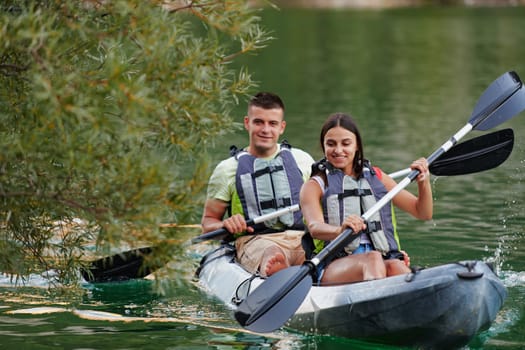 A young couple enjoying an idyllic kayak ride in the middle of a beautiful river surrounded by forest greenery.