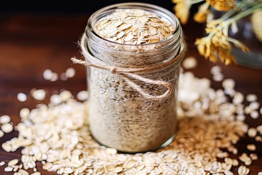 A jar of oatmeal is on a table with a spoon and a pile of oatmeal. The jar is half full and the oatmeal is scattered around it