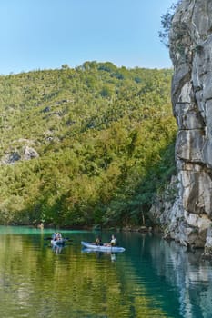 A group of friends enjoying having fun and kayaking while exploring the calm river, surrounding forest and large natural river canyons.