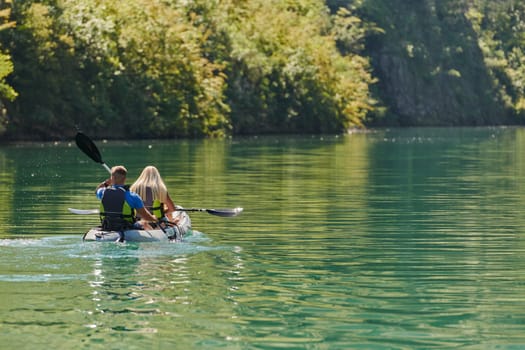 A young couple enjoying an idyllic kayak ride in the middle of a beautiful river surrounded by forest greenery.