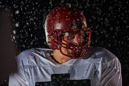 American Football Field: Lonely Athlete Warrior Standing on a Field Holds his Helmet and Ready to Play. Player Preparing to Run, Attack and Score Touchdown. Rainy Night with Dramatic Fog, Blue Light.