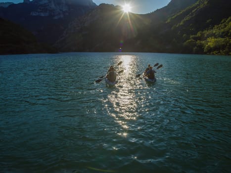 A group of friends enjoying fun and kayaking exploring the calm river, surrounding forest and large natural river canyons during an idyllic sunset