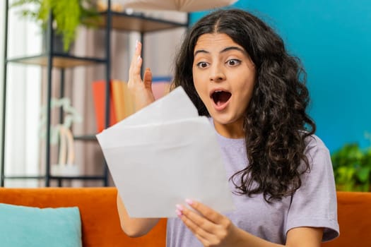 Happy Indian woman open envelope letter, reading it, wow. Career growth advance promotion, bank loan approve, successful admission to university monetary award invitation great news, lottery game win