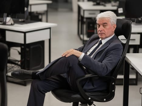 Portrait of a serious mature business man sitting in a chair in the office