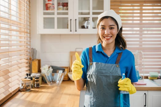 Ready for home cleaning smiling woman in uniform holds spray bottle. Emphasizing housekeeping and hygiene. Clean disinfect home care. maid with liquid.