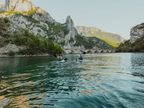 A group of friends enjoying having fun and kayaking while exploring the calm river, surrounding forest and large natural river canyons.