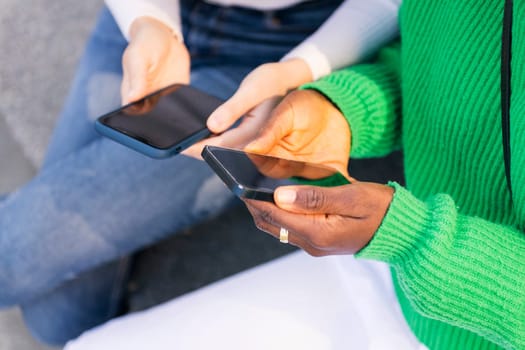 close up of the hands of two unrecognizable women using their mobile phones, concept of technology of communication and modern lifestyle