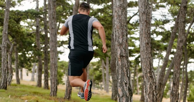 An unwavering man dashes through perilous forest paths, skillfully hurdling over wooden obstacles with determination and agility, epitomizing courage and athleticism