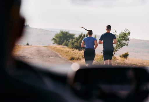 A romantic couple is captured running outdoors from the perspective of a car, embodying adventure and togetherness in their journey