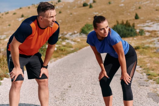 A couple is captured in a moment of relaxation and rejuvenation, taking a break after an intense morning run to recharge and enjoy the tranquility of their surroundings