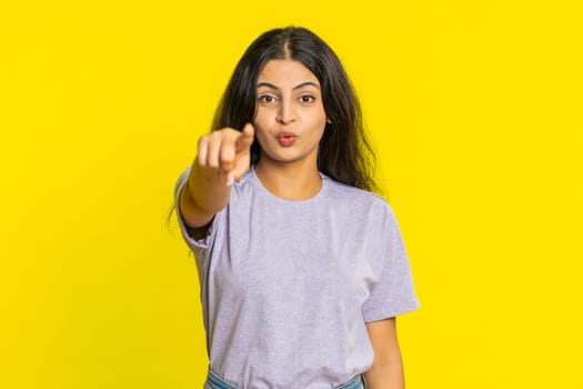 I choose you. Indian smiling woman pointing finger to camera and looking with playful happy expression, making winner choice, showing direction. Arabian young girl isolated on yellow studio background