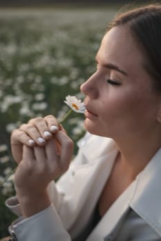 A woman is sitting in a field of flowers and smelling a flower. Concept of peace and tranquility, as the woman is surrounded by nature and taking a moment to appreciate its beauty