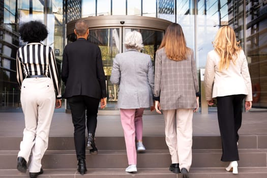 Five caucasian female business colleagues talking happily, co-workers talking walking to enter the office building where they workview of five businesswomen walking to enter office building outdoors.