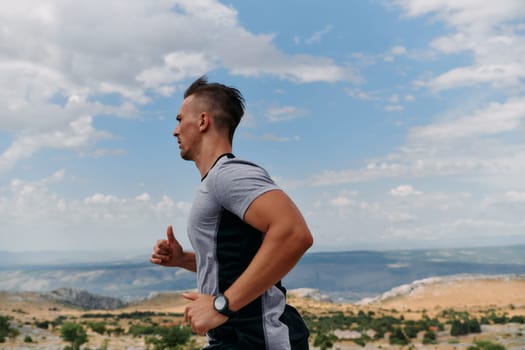 A muscular male athlete runs along a rugged mountain path at sunrise, surrounded by breathtaking rocky landscapes and natural beauty.