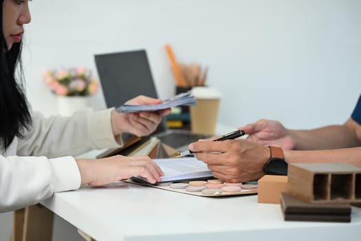 Side view of female client paying cash to male contractor after signed contract.