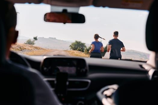 A romantic couple is captured running outdoors from the perspective of a car, embodying adventure and togetherness in their journey