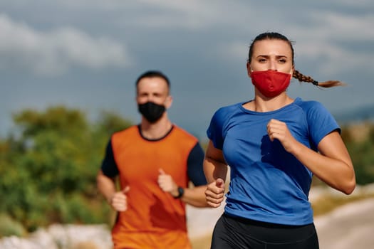 Couple running in nature at morning wearing protective face masks.